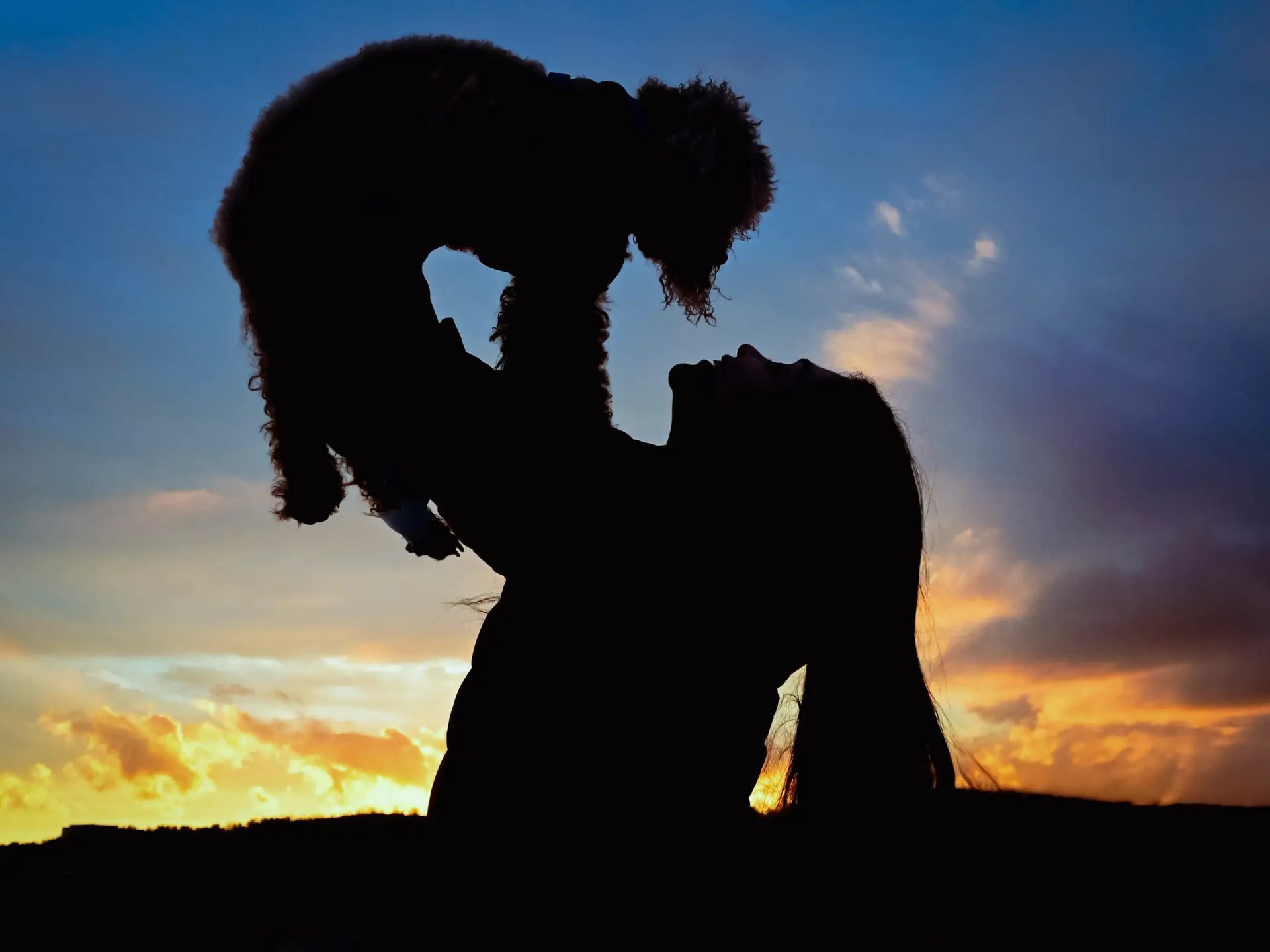 Mujer alzando perrito al atardecer fotografía de mascotas